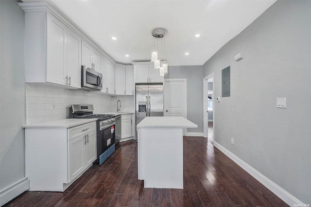 kitchen with hanging light fixtures, baseboard heating, dark hardwood / wood-style flooring, white cabinets, and appliances with stainless steel finishes