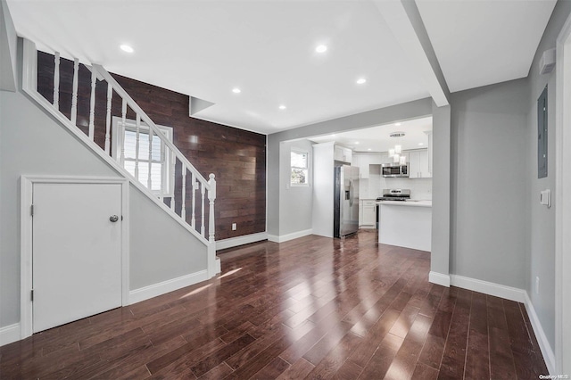 unfurnished living room with wood walls and dark wood-type flooring