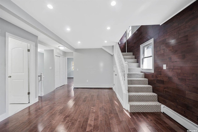 interior space featuring wood-type flooring, a baseboard radiator, and wood walls