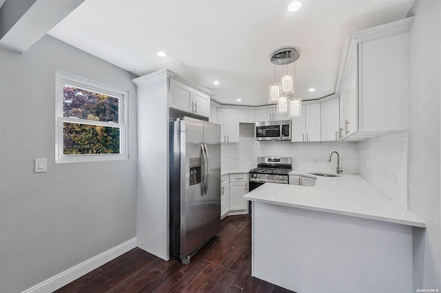 kitchen with sink, dark wood-type flooring, decorative light fixtures, white cabinets, and appliances with stainless steel finishes