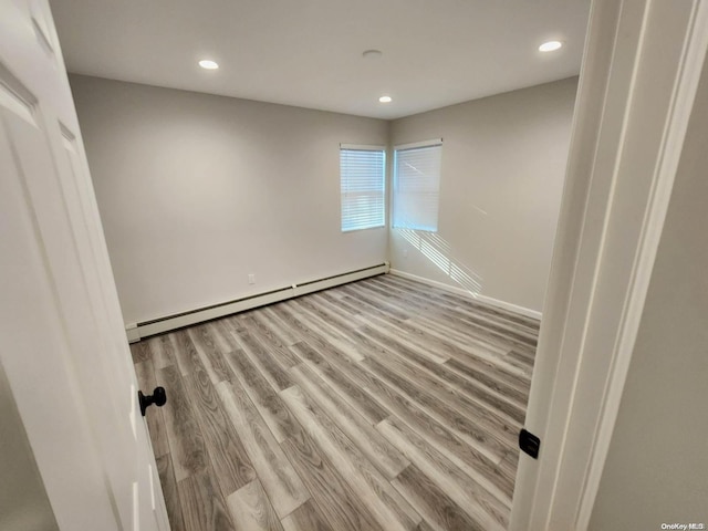 spare room featuring a baseboard radiator and light hardwood / wood-style flooring