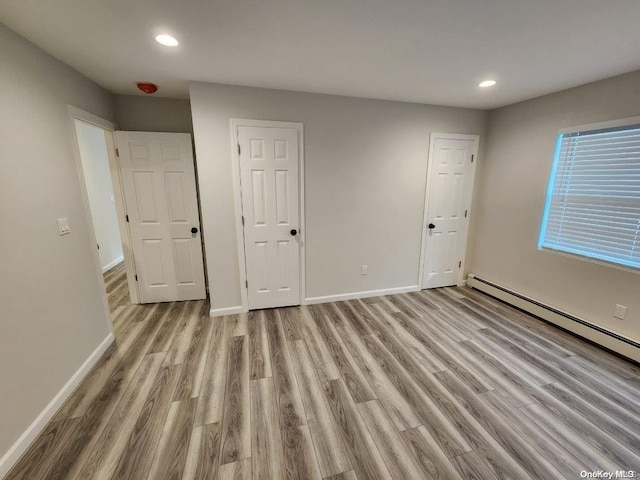 unfurnished bedroom featuring a baseboard radiator and light wood-type flooring