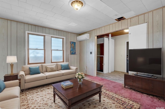 living room with a wall unit AC, wood walls, and light carpet