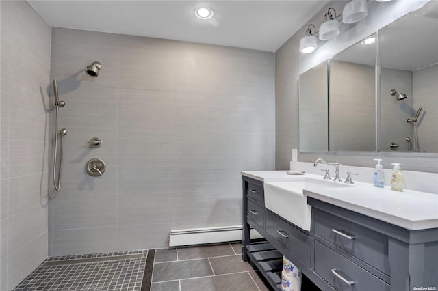 bathroom featuring a tile shower, tile patterned flooring, vanity, and a baseboard heating unit