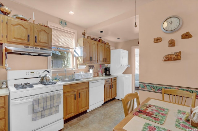 kitchen with stacked washer and clothes dryer, a wealth of natural light, sink, and white appliances