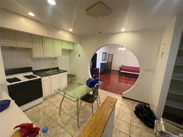 kitchen with decorative backsplash, light hardwood / wood-style floors, white range with gas stovetop, and sink