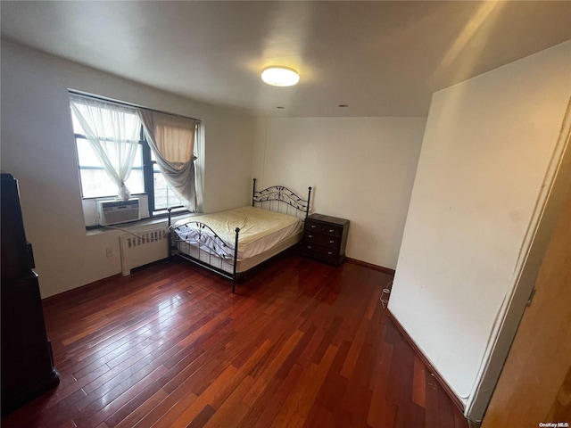 unfurnished bedroom featuring cooling unit, radiator heating unit, and dark wood-type flooring