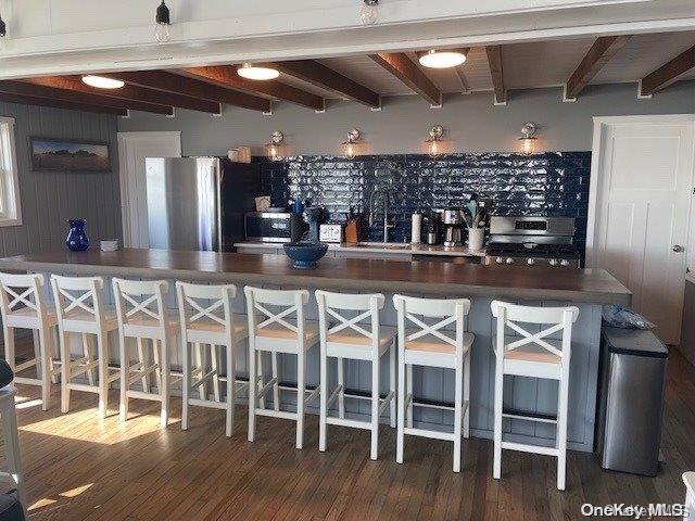 bar featuring beamed ceiling, dark hardwood / wood-style floors, sink, and stainless steel appliances