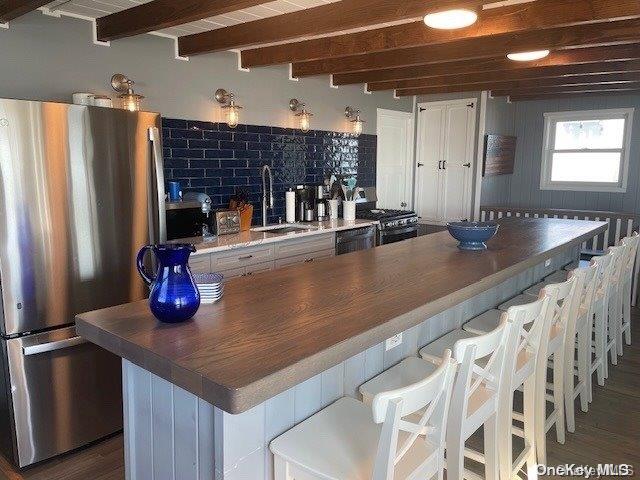 kitchen featuring white cabinetry, sink, dark wood-type flooring, stainless steel appliances, and a kitchen breakfast bar