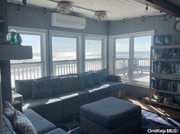 living room with a water view, an AC wall unit, and plenty of natural light