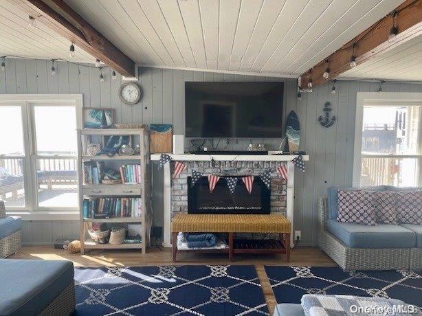 sitting room with a fireplace, wooden walls, hardwood / wood-style flooring, wooden ceiling, and beamed ceiling