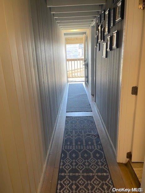 hallway with light hardwood / wood-style floors and wooden walls