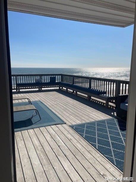 wooden deck featuring a water view and a beach view