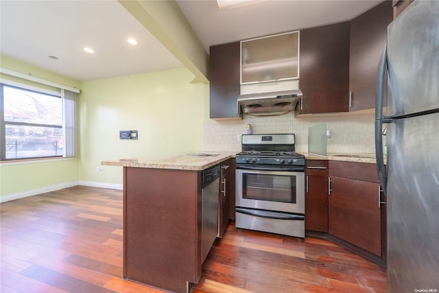 kitchen with tasteful backsplash, kitchen peninsula, stainless steel appliances, and dark wood-type flooring