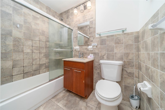 full bathroom with tile patterned floors, vanity, shower / bath combination with glass door, tile walls, and toilet