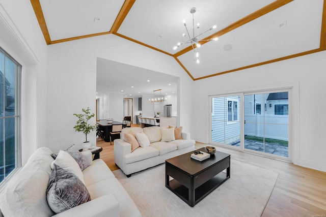 living room featuring crown molding, light hardwood / wood-style flooring, high vaulted ceiling, and an inviting chandelier