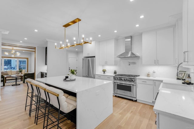 kitchen with white cabinetry, a kitchen island, wall chimney range hood, and premium appliances