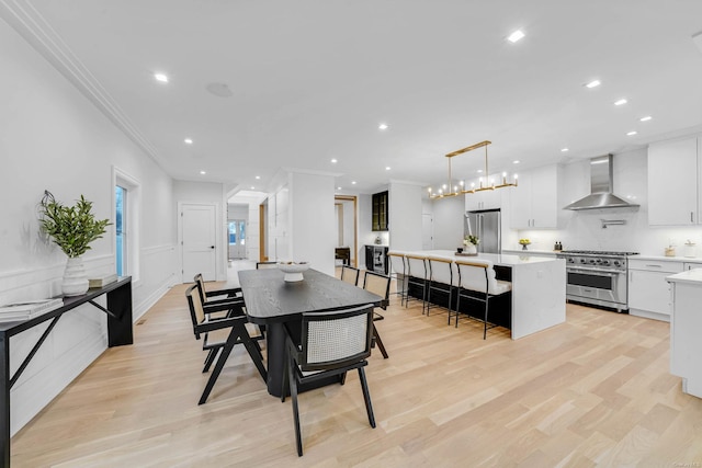 dining area with light hardwood / wood-style floors and ornamental molding