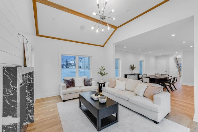 living room featuring lofted ceiling, an inviting chandelier, ornamental molding, and light hardwood / wood-style flooring