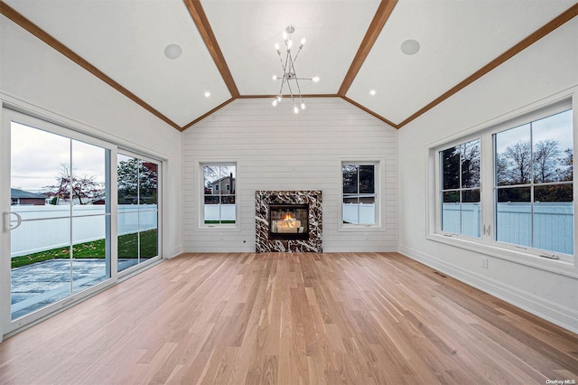 unfurnished living room featuring light wood-type flooring, lofted ceiling, a fireplace, and a chandelier