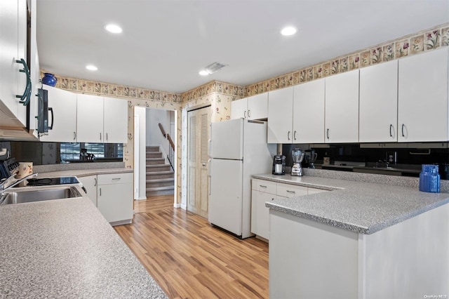 kitchen featuring white fridge, light hardwood / wood-style floors, decorative backsplash, and white cabinetry