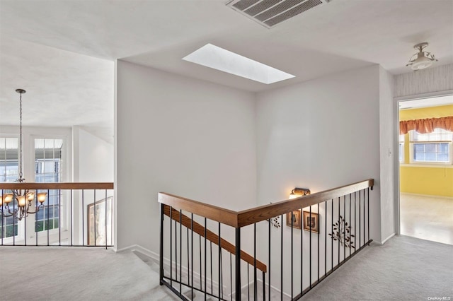 hallway featuring a skylight, carpet, and an inviting chandelier