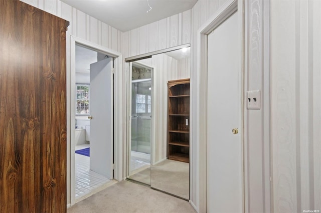 hall featuring wood walls and light colored carpet