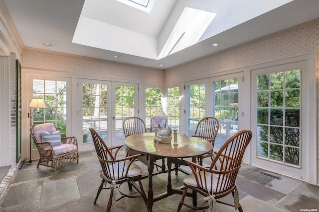 dining space with french doors, lofted ceiling with skylight, and ornamental molding