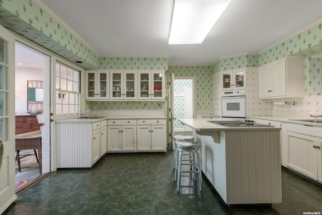 kitchen featuring oven, a center island, white cabinetry, and crown molding