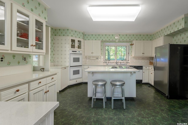 kitchen with a breakfast bar area, white cabinetry, a kitchen island, and white appliances