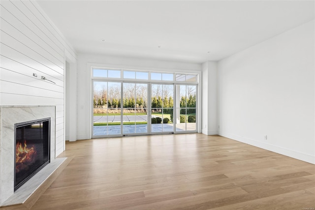 unfurnished living room with a high end fireplace and light wood-type flooring