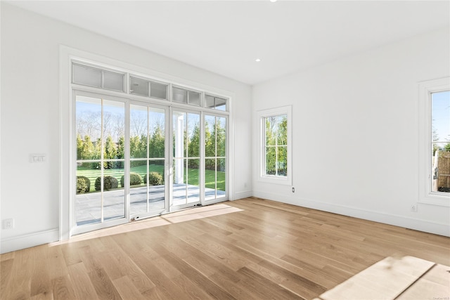 unfurnished room featuring light wood-type flooring and a healthy amount of sunlight