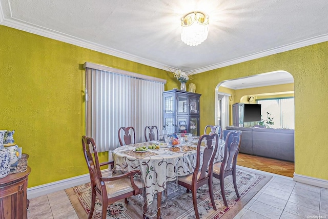 tiled dining room with ornamental molding and a textured ceiling