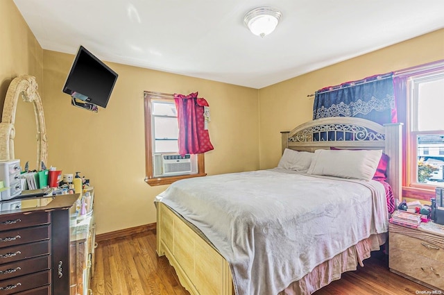 bedroom with hardwood / wood-style flooring, multiple windows, and cooling unit