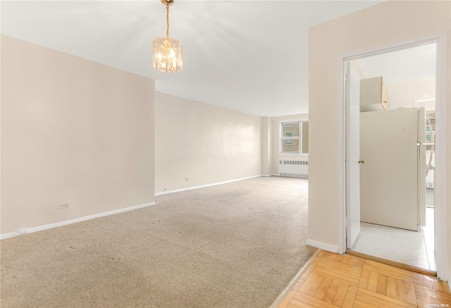 empty room with radiator, carpet floors, and a chandelier