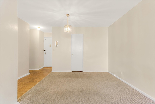 spare room featuring light parquet floors and a chandelier