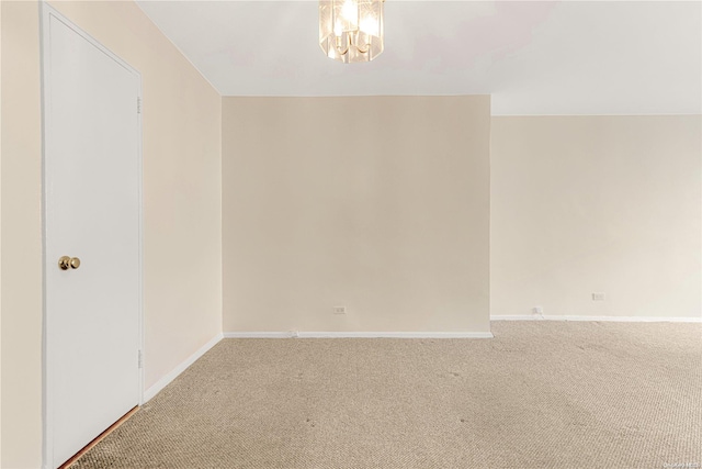 spare room featuring carpet and an inviting chandelier