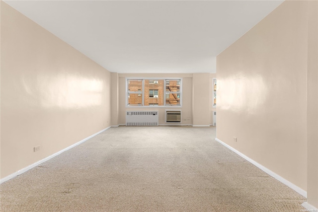 carpeted spare room with a wall mounted AC and radiator