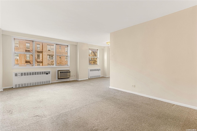 unfurnished living room featuring a wall mounted air conditioner, radiator heating unit, and carpet floors