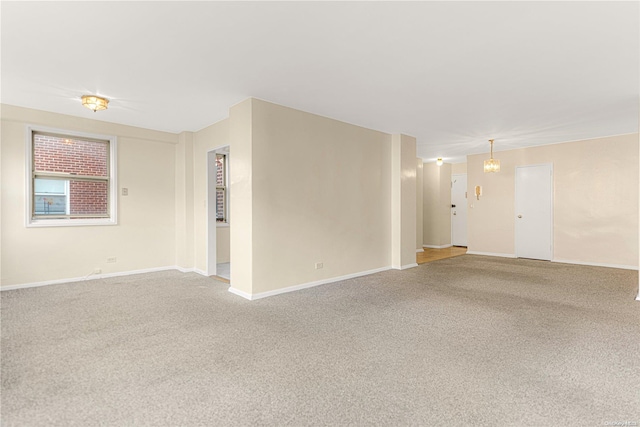 carpeted spare room with a chandelier