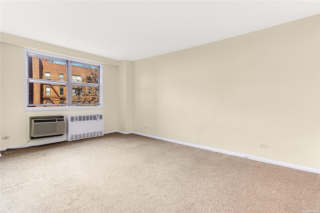 carpeted spare room with a wall mounted AC and radiator heating unit