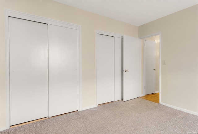 unfurnished bedroom with light carpet and multiple closets