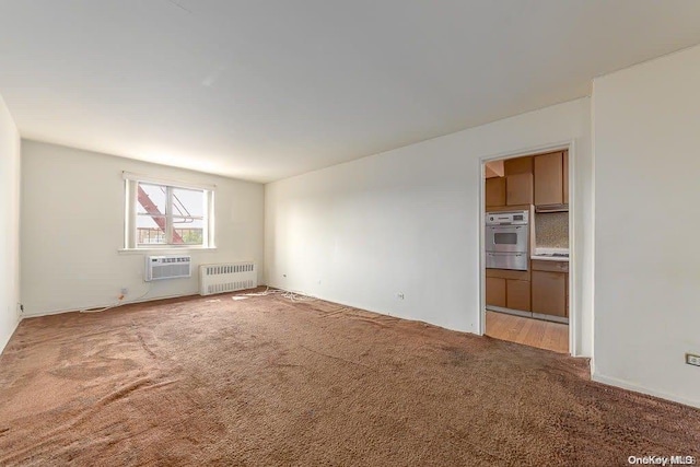 carpeted empty room with a wall unit AC and radiator heating unit