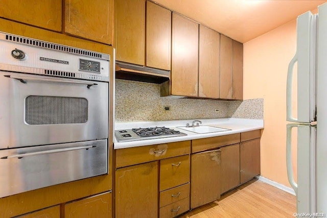 kitchen featuring appliances with stainless steel finishes, backsplash, light hardwood / wood-style flooring, and sink