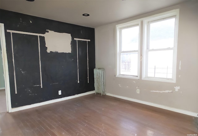 empty room featuring radiator, dark wood-type flooring, and a healthy amount of sunlight