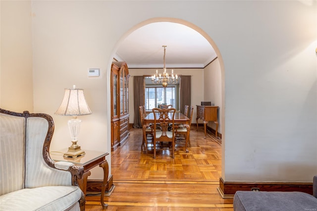 dining space featuring crown molding, light parquet floors, and a notable chandelier