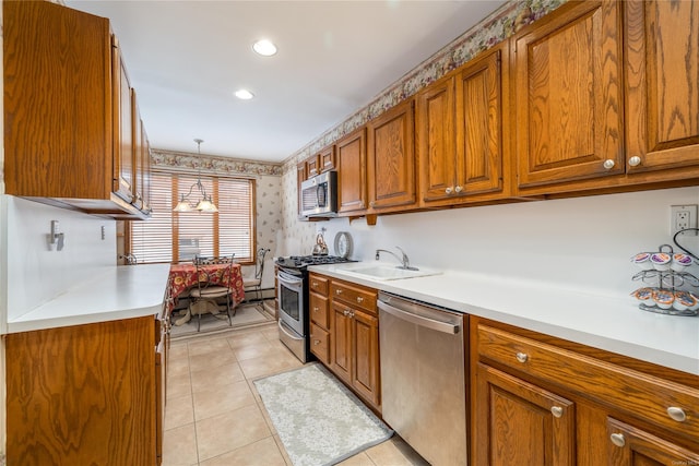 kitchen with sink, light tile patterned floors, hanging light fixtures, and appliances with stainless steel finishes