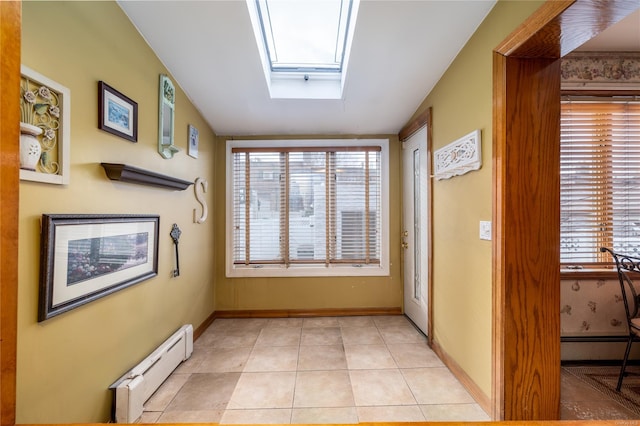 hall featuring light tile patterned flooring, a skylight, and a baseboard heating unit