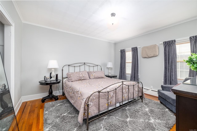 bedroom featuring hardwood / wood-style floors, a baseboard heating unit, and crown molding