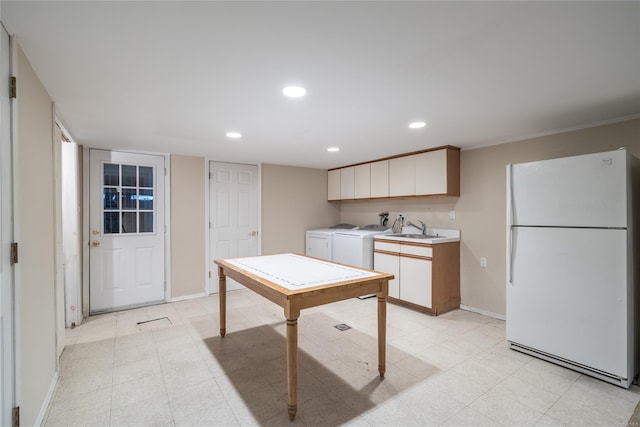 kitchen with washer and dryer, white refrigerator, white cabinetry, and sink